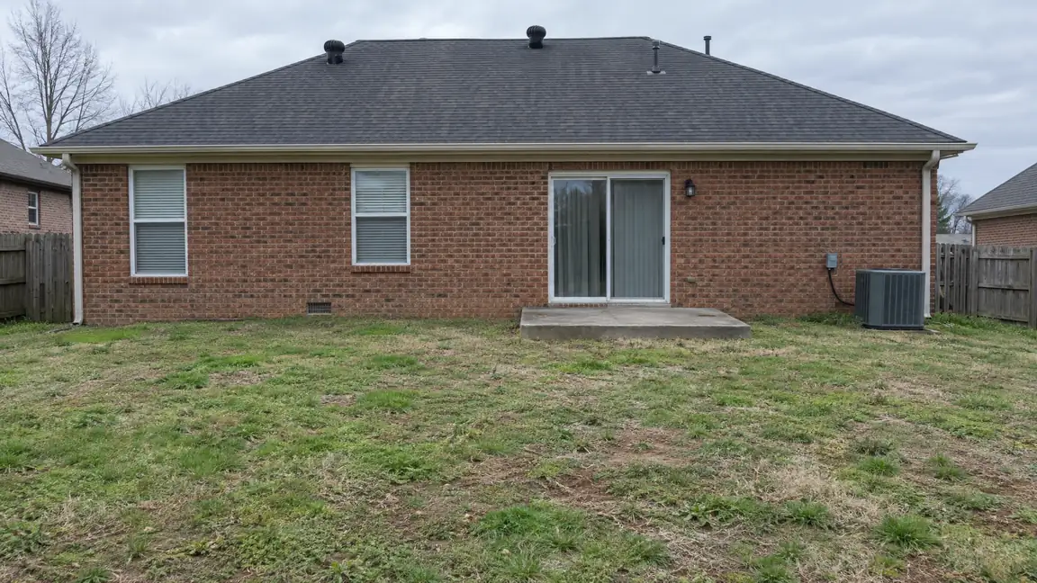 Before: Bare Stoop | Music City Deck & Fence Before: The back of a brick home with a plain concrete stoop and an empty patchy lawn