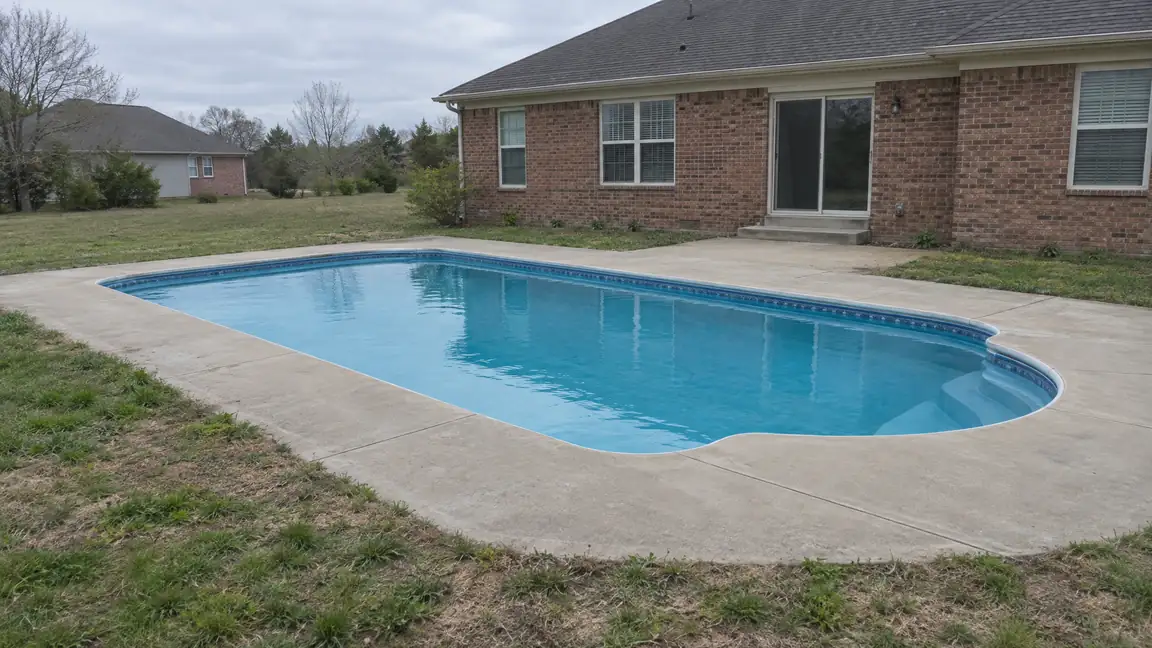 Before: A backyard in-ground pool with bare concrete around it and no fence or furniture