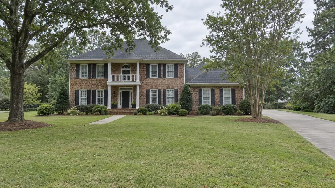 Before: The front yard of a two-story brick home with an open lawn and no fence or gate