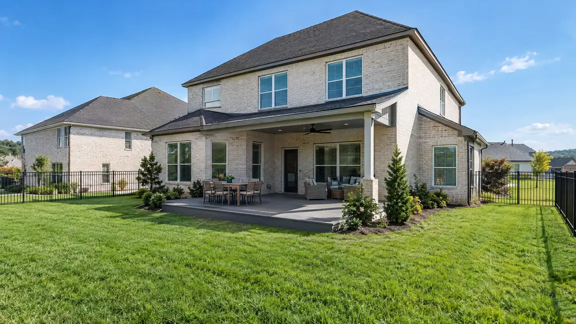 A new construction home with a ground-level composite deck, a black aluminum fence and fresh green sod
