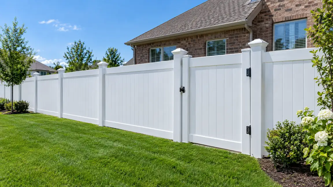 White Vinyl Privacy Fence | Music City Deck & Fence A crisp white vinyl privacy fence with a matching gate and post caps along a neat lawn in front of a brick home